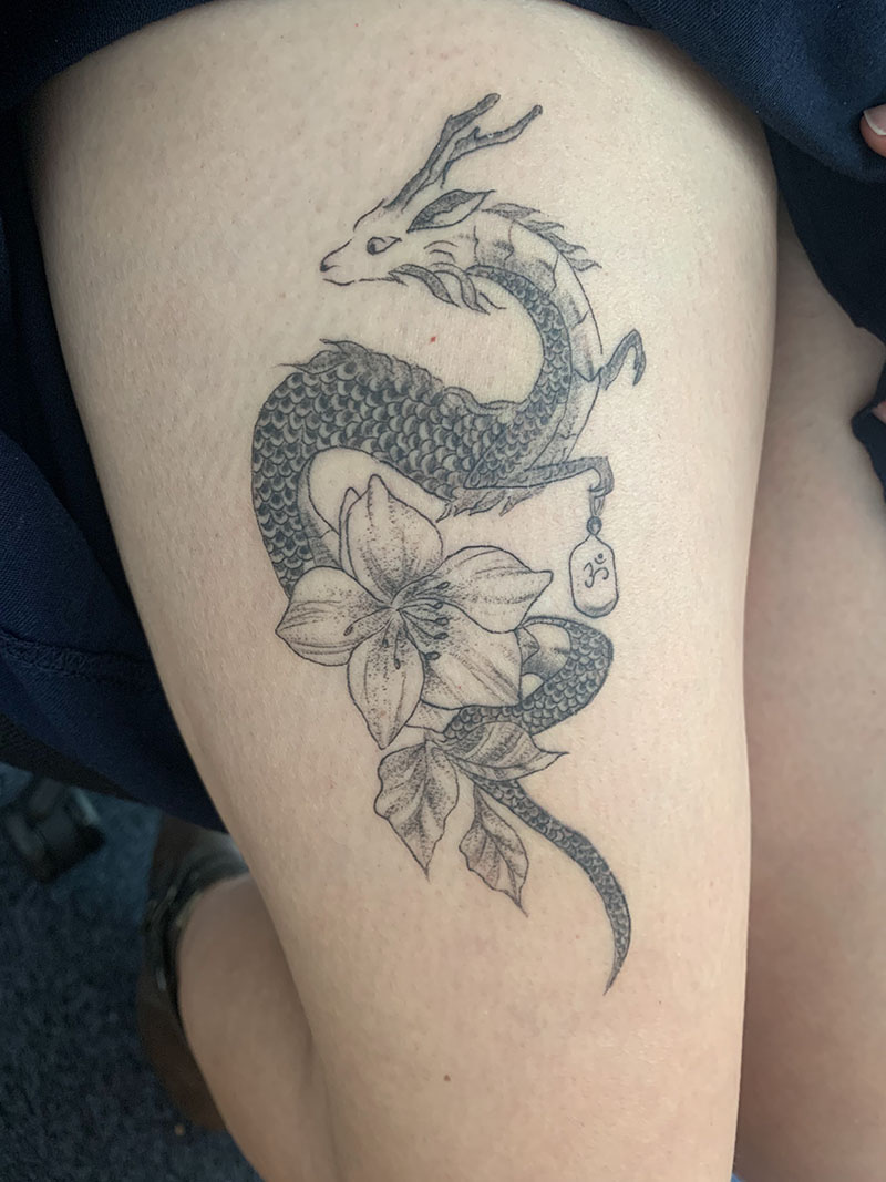 Tatouage blackwork dragon et fleurs sur la cuisse
