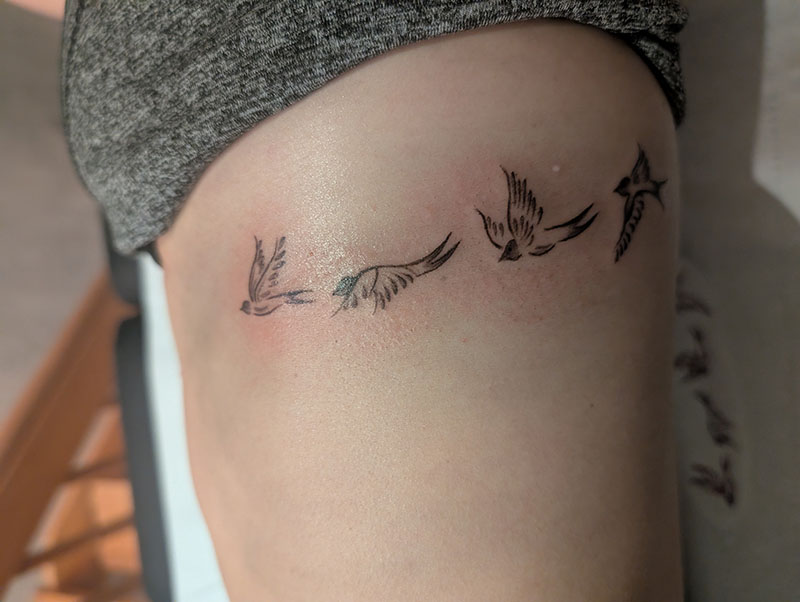 Tatouage fine line hirondelles en vol sur les côtes
