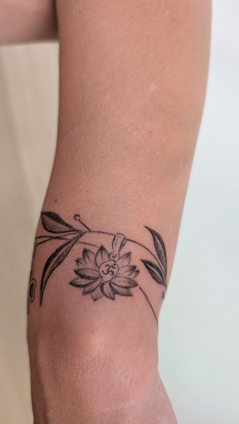 Tatouage fine line lotus bracelet autour du poignet