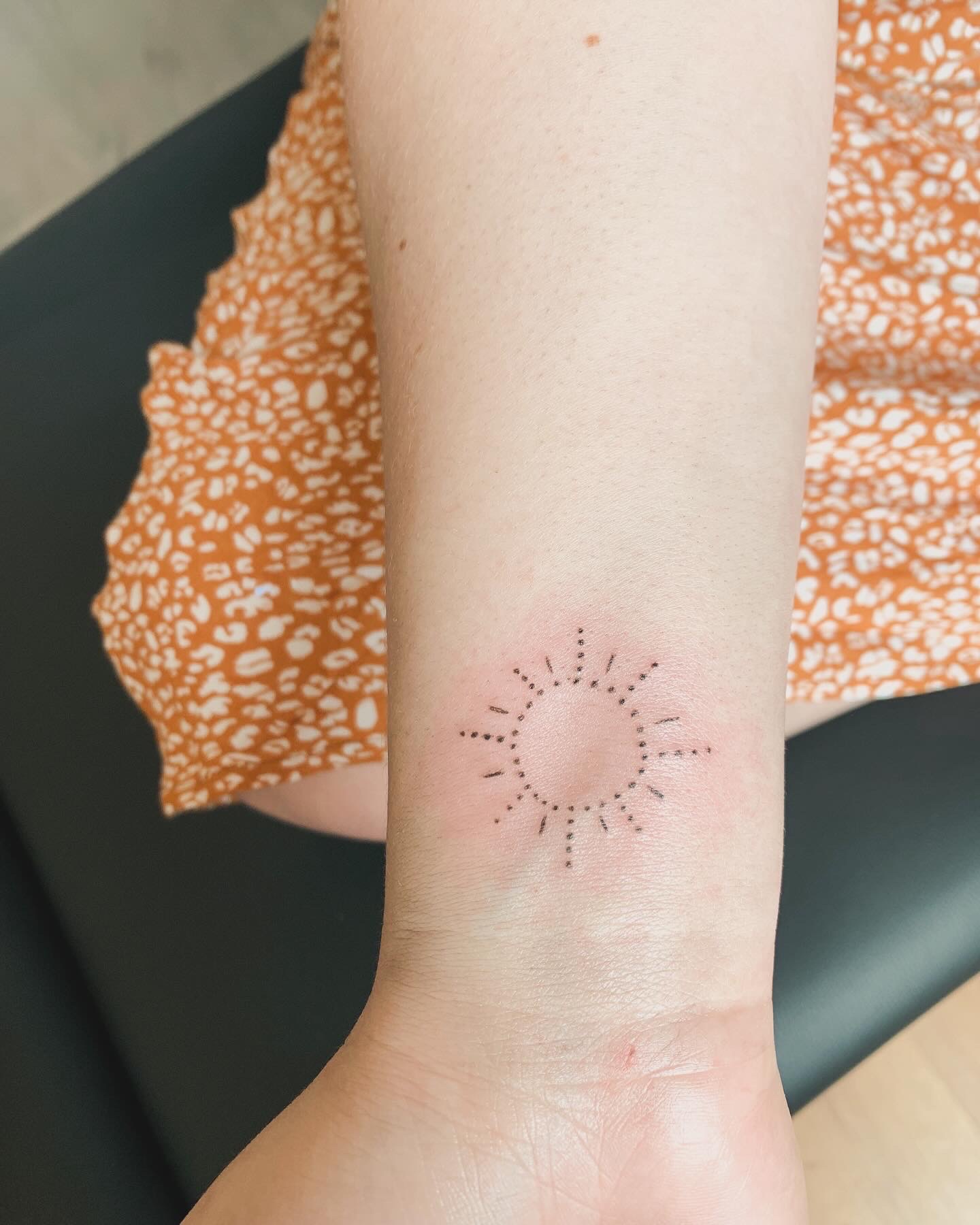 Tatouage fine line soleil minimaliste au poignet